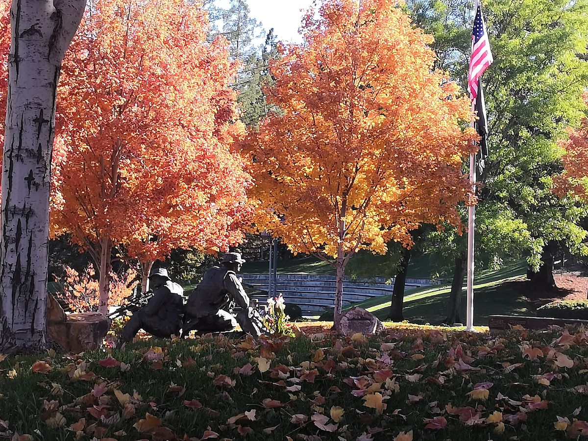 Bronze soldiers at the Veterans Memorial in Memorial Park, under autumn trees